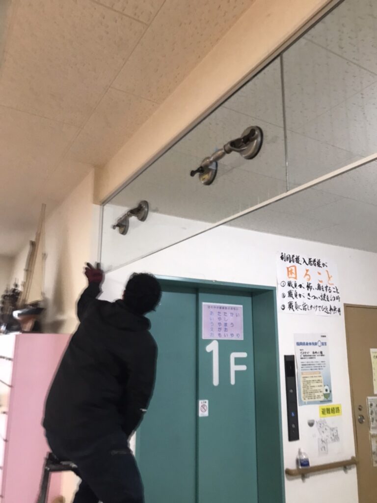 新しい防煙垂れ壁ガラスに吸盤を取り付けている様子
