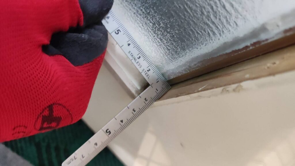 室内ドアの縦額縁を外して新しいガラスをはめ込む作業