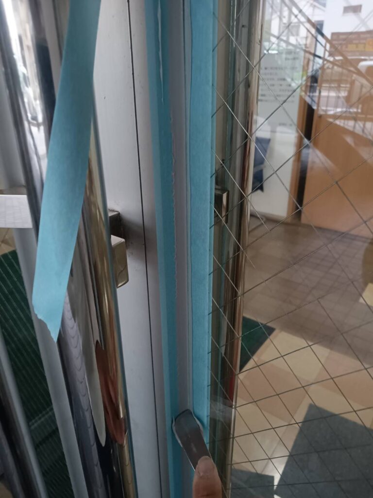 店舗入口ドアの網入りガラスをコーキングで固定する作業 下関市