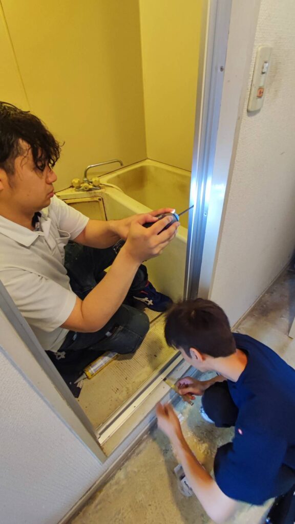 新しい浴室中折れ戸の枠を既設枠へ固定している様子
