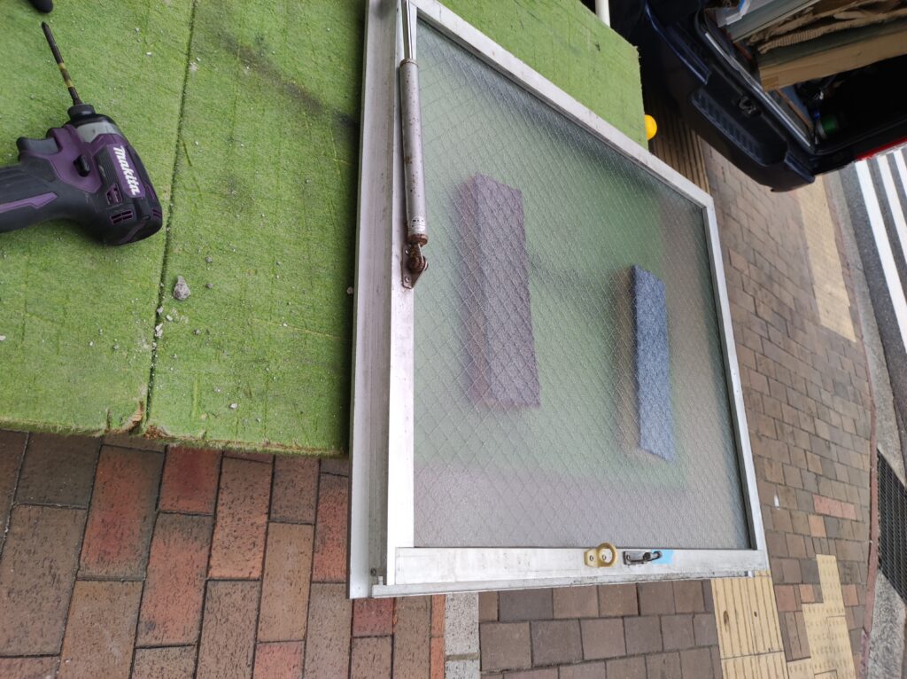 外開き窓を分解して網入りガラスを交換している作業風景
