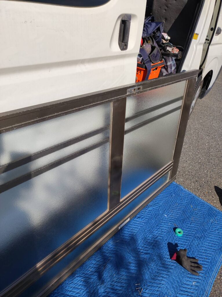 玄関引戸に新しい型板ガラスを取り付けている施工中写真