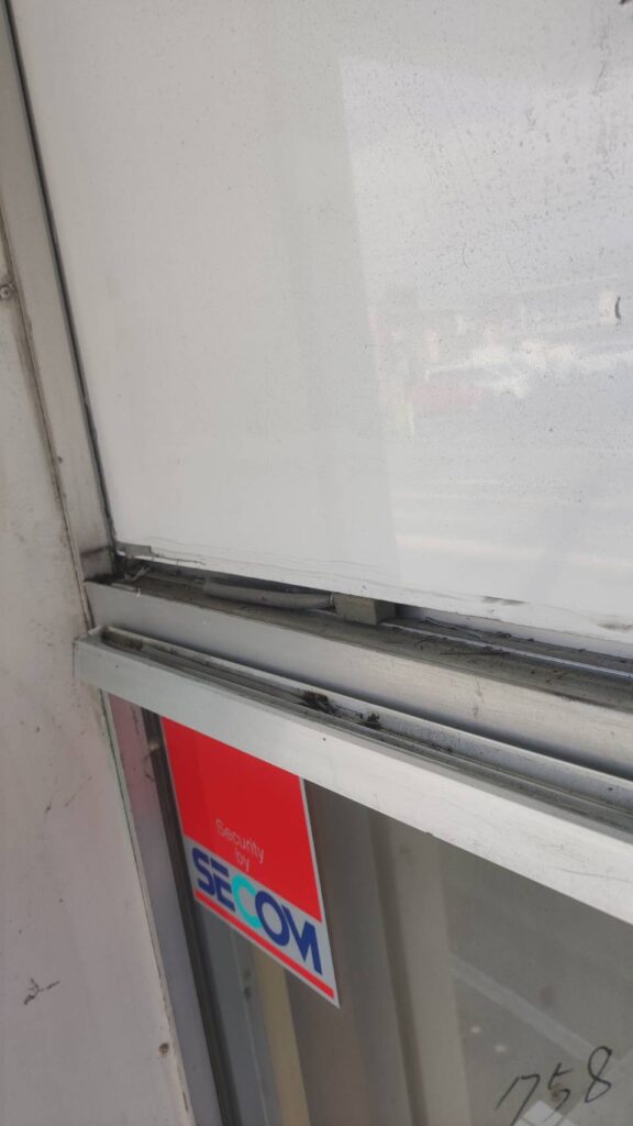 山口市の店舗FIX窓で既存コーキングをカッターで切り離している作業